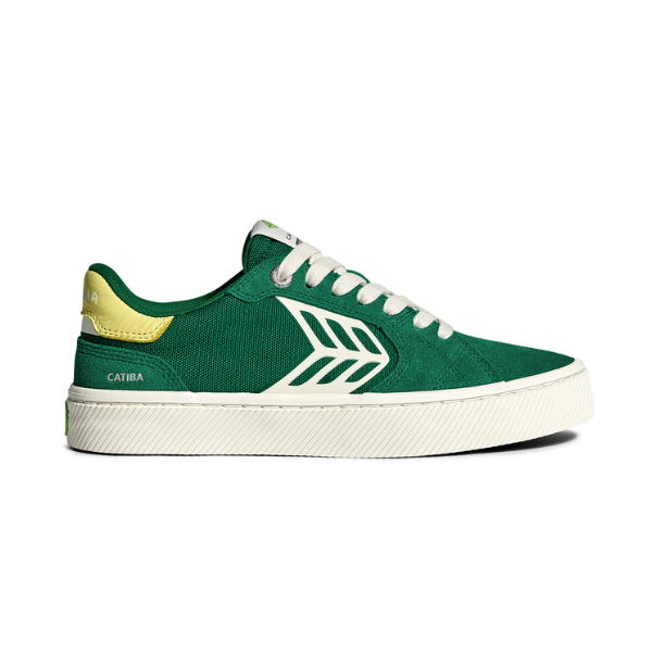 Green sneaker with white laces and a yellow heel on a white background
